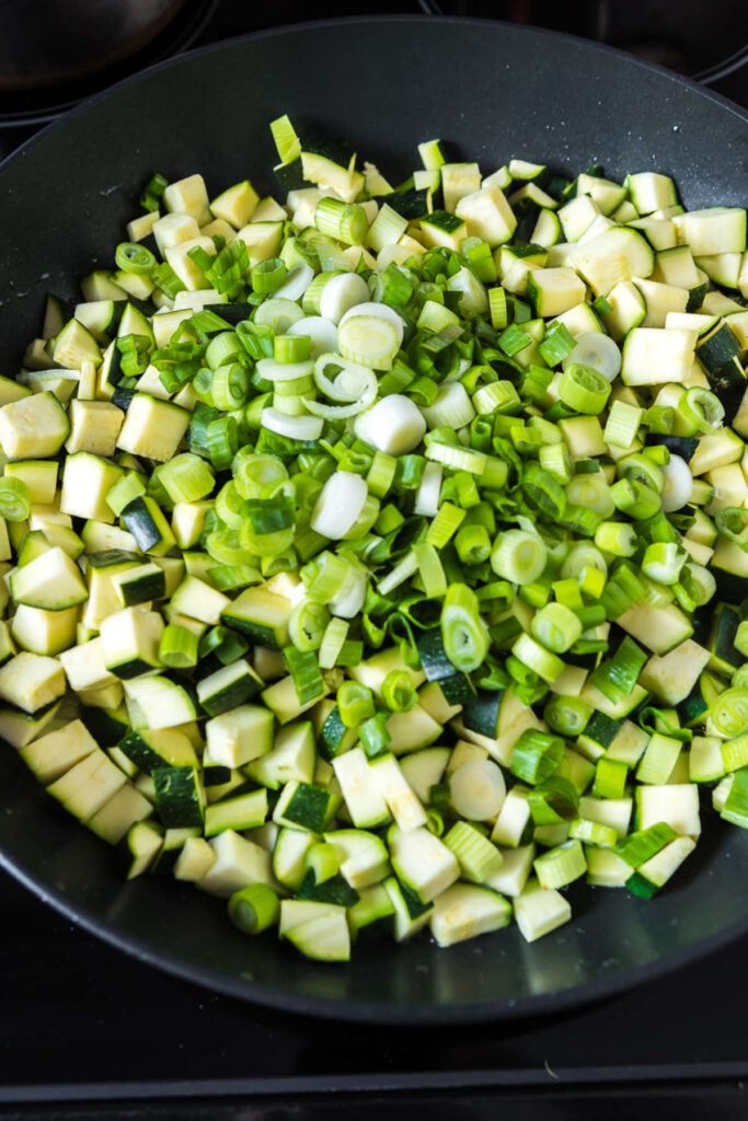 Sautéed zucchini and green onions in a pan. How to make Fresh Zucchini, Herb, and Rice Casserole Recipe.