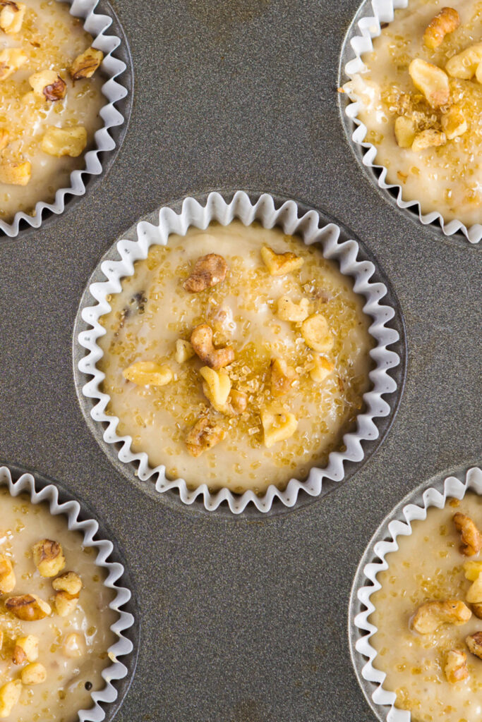 Banana muffins with walnuts and sour cream unbaked in muffin tin topped with sugar
